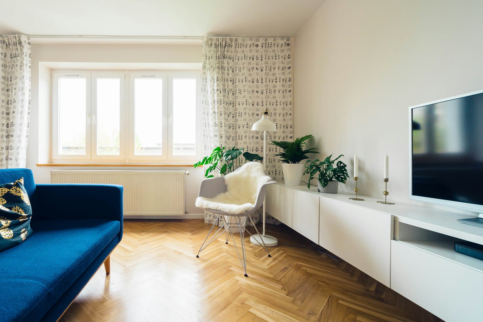 Bright living room with a blue sofa and a white TV unit